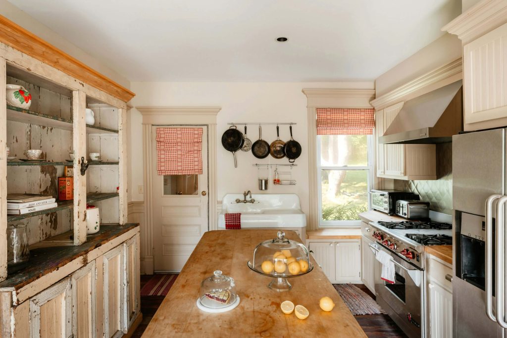 Farmhouse kitchen with a large butcher block island, cream cabinets, cast iron pans, and a vintage apron sink