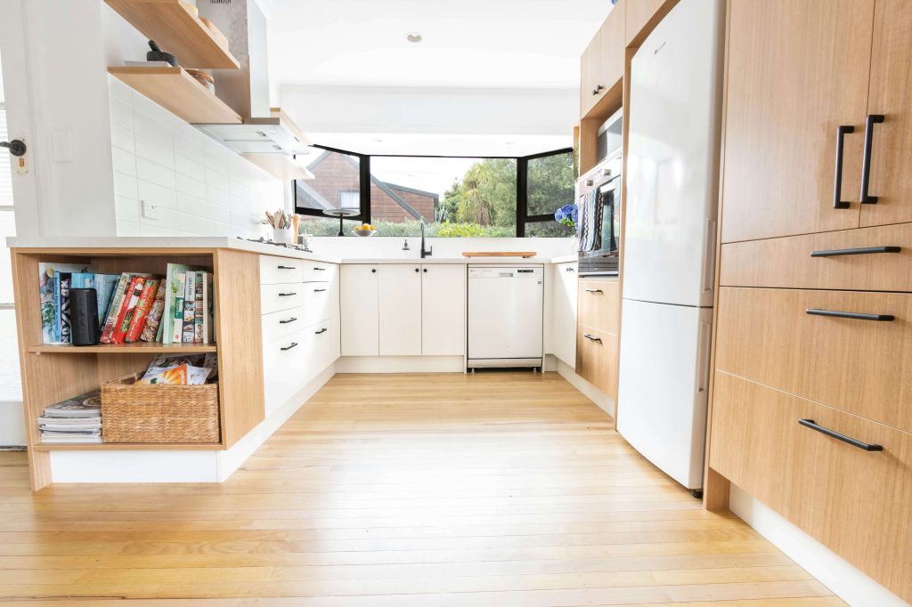 Modern kitchen with light hardwood flooring, white cabinets, wood accents, and open shelving