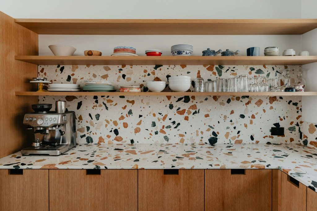 Kitchen with a terrazzo slab backsplash and matching countertop, wood cabinets, and open shelving