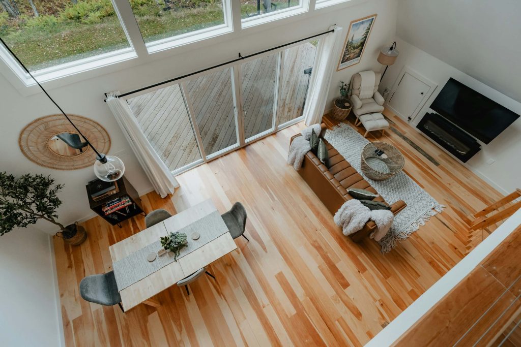 Overhead view of an open concept living and dining room with light hardwood floors, modern furniture, and large windows