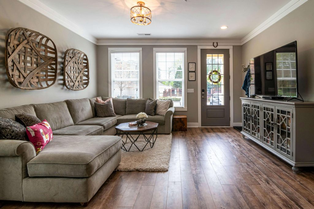 Living room with dark wide-plank hardwood floors, gray sectional sofa, neutral walls, and decorative wall art