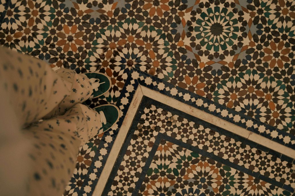 Person standing on decorative warm-toned tile floor with geometric pattern, showing comfortable tile surface with warm color tones