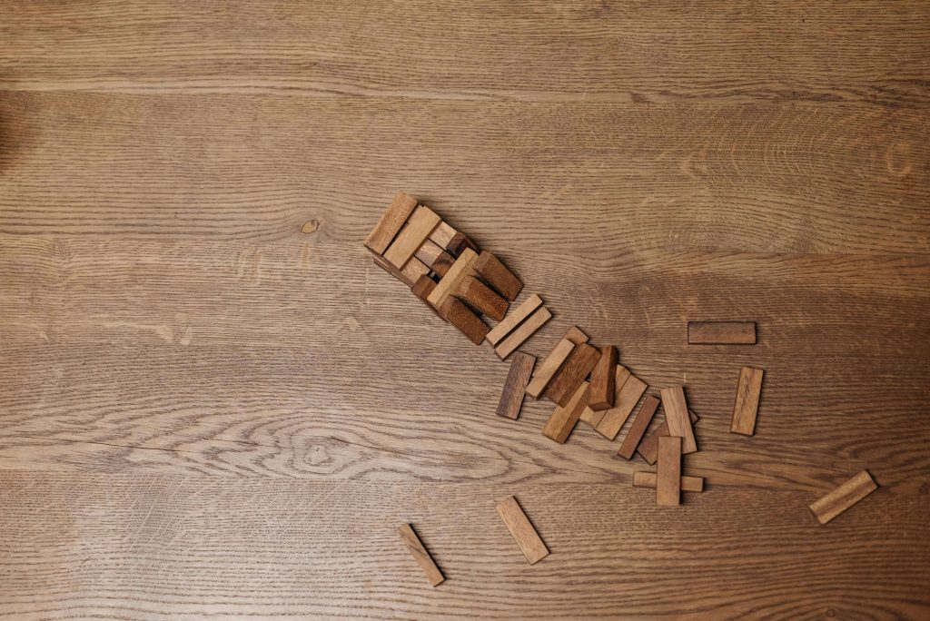 Fallen wooden blocks scattered on a wide-plank oak hardwood floor showing natural grain and texture